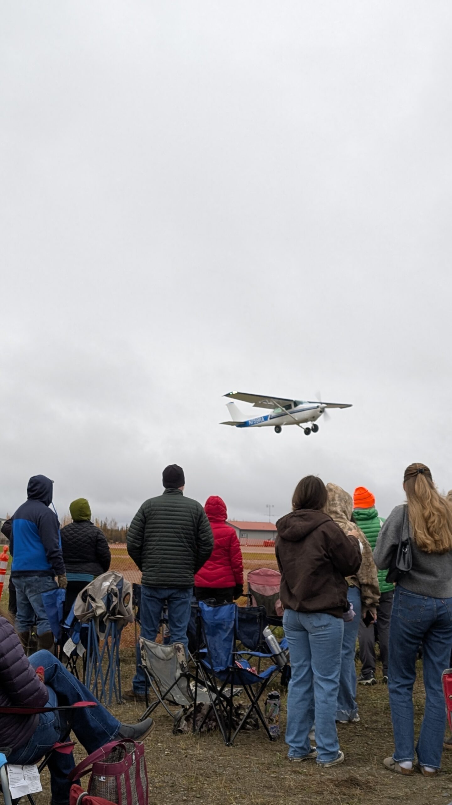 a crowd watches a plane fly by at the Pumpkin Drop